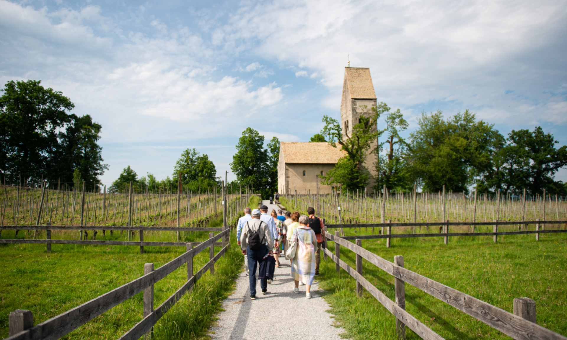 Eine Gruppe unterwegs auf der Insel Ufnau mit Kirche im Hintergrund.